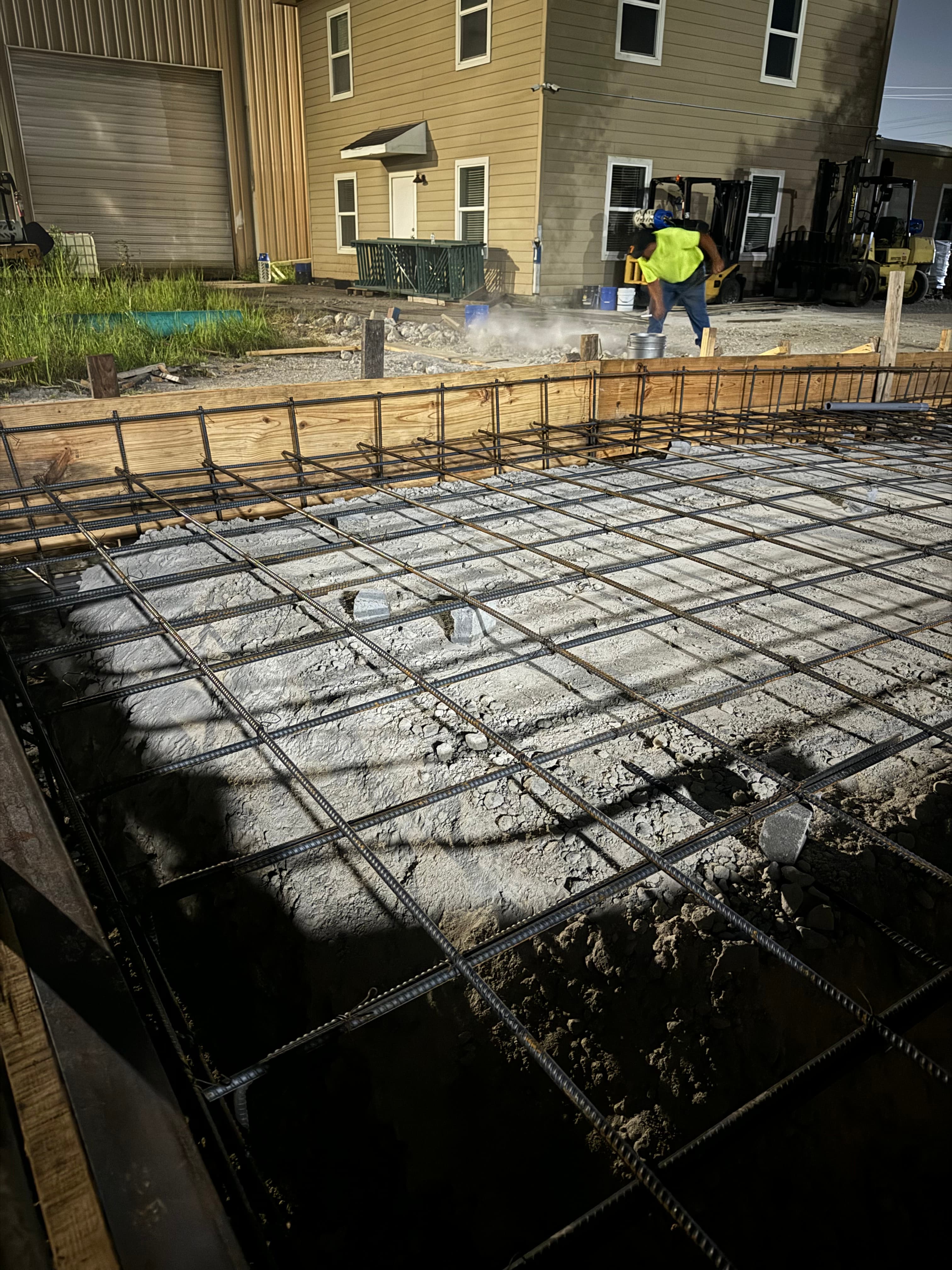 Foundation wall form and rebar setup lit up on a night job site