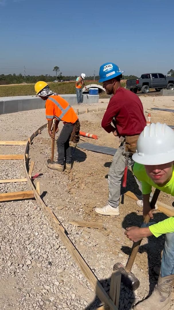 Crew hand-finishing a curved commercial curb and sidewalk pour