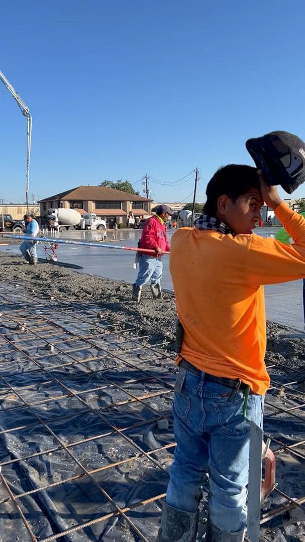 Crew finishing a large commercial concrete slab pour in daylight
