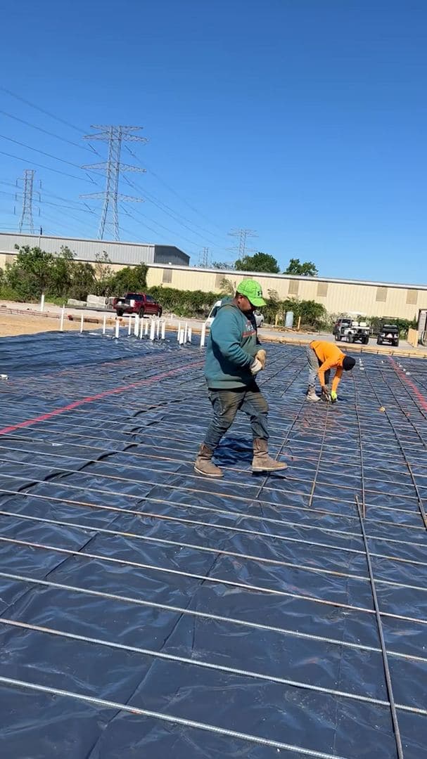 Crew tying a rebar grid before a large slab pour