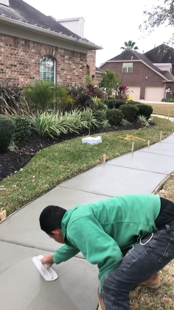 Hand-finishing a curved concrete sidewalk in front of a Houston-area home