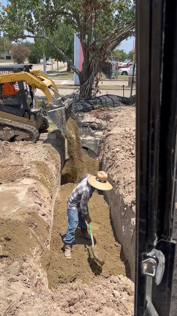 Crew installing drainage pipe in a trench before backfilling