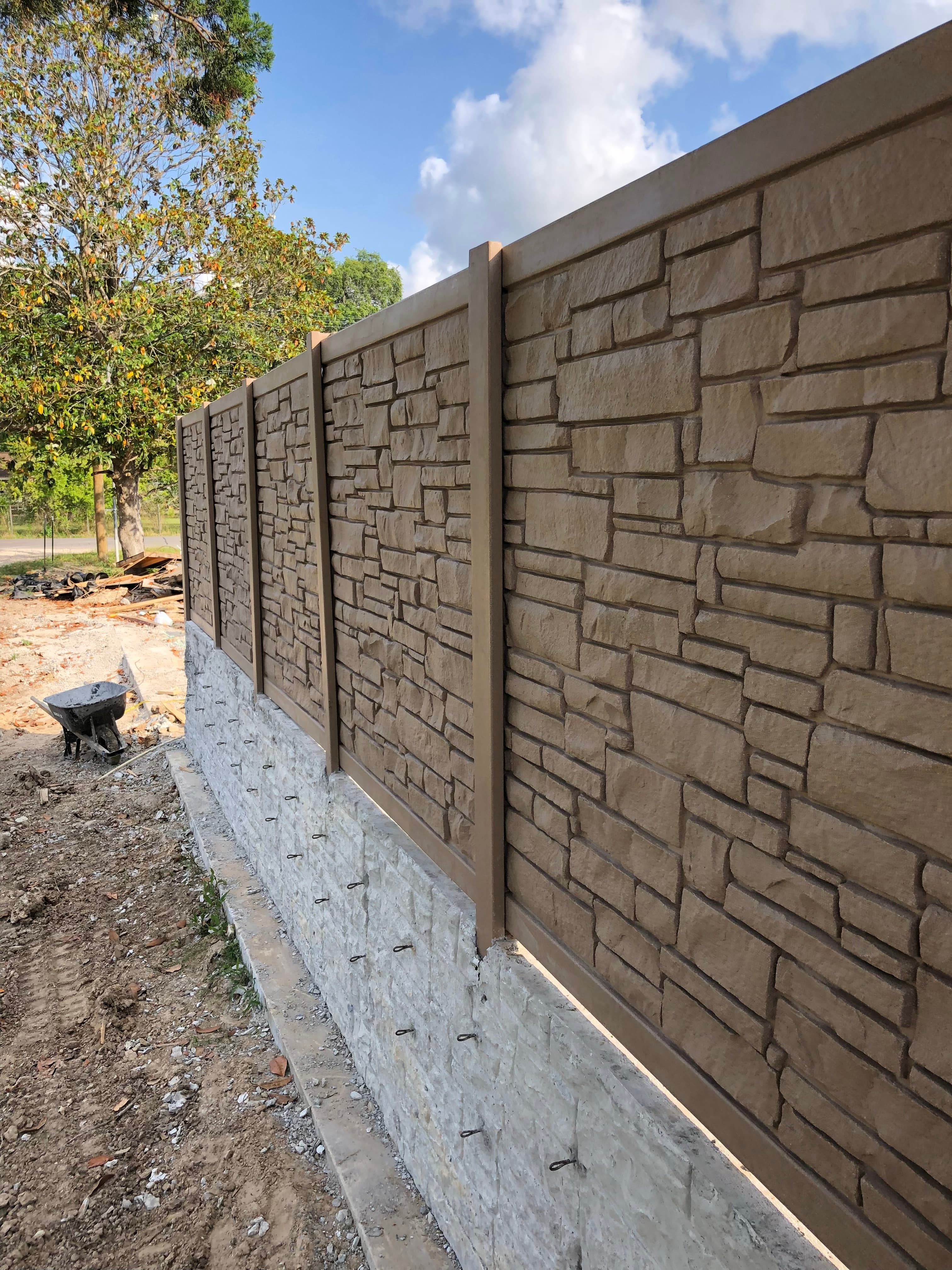 Precast stone-look concrete fence wall installed on a poured concrete footing